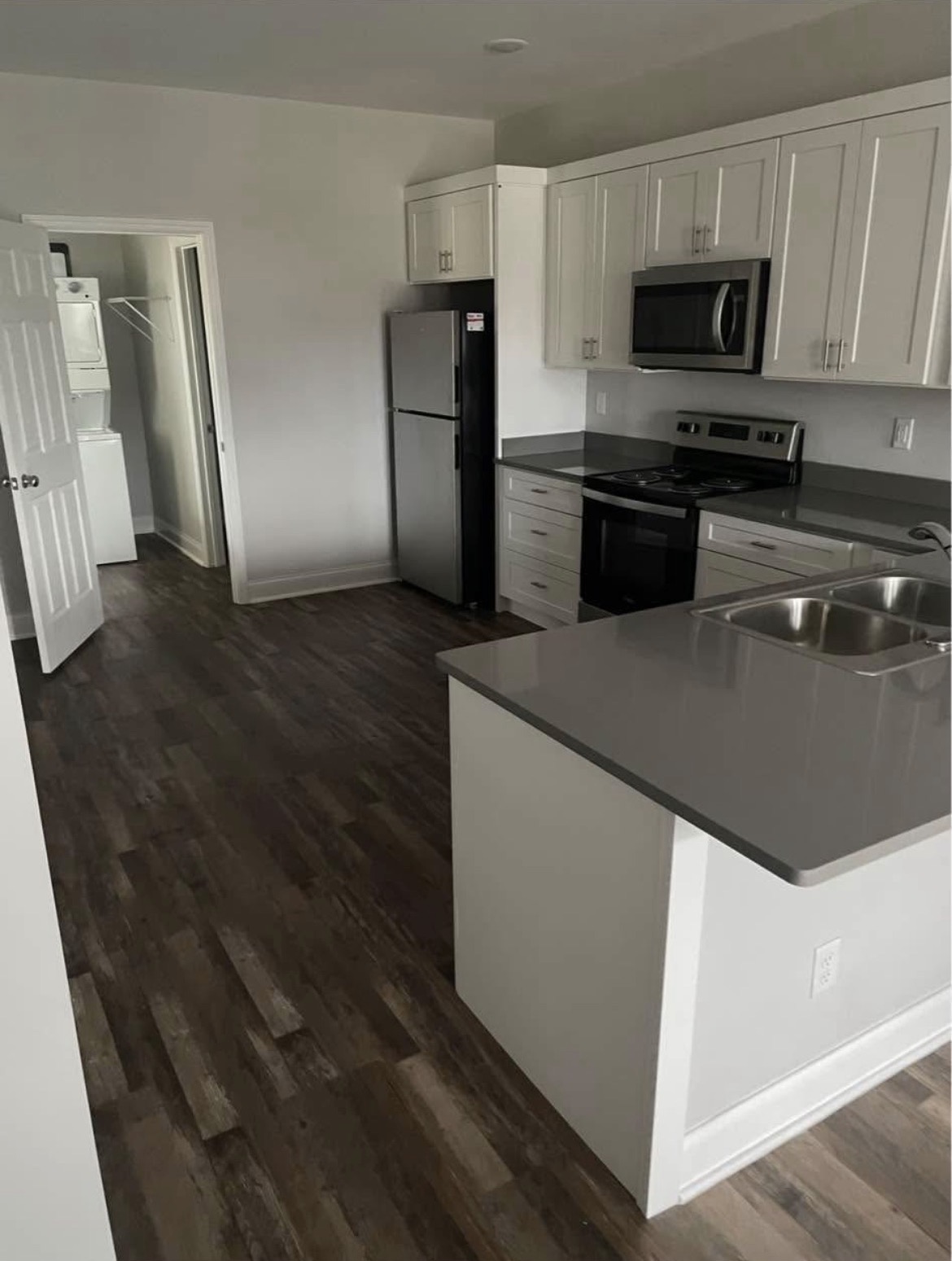 Remodeled kitchen with white shaker cabinets, island and dark wood-look flooring
