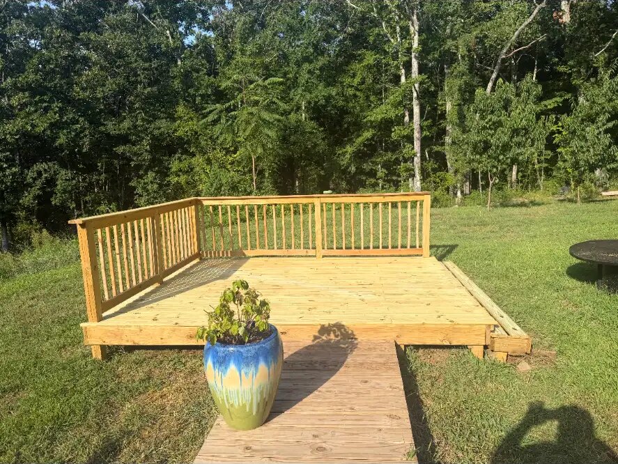 Freshly built backyard deck platform with vertical-spindle railings and a plank walkway