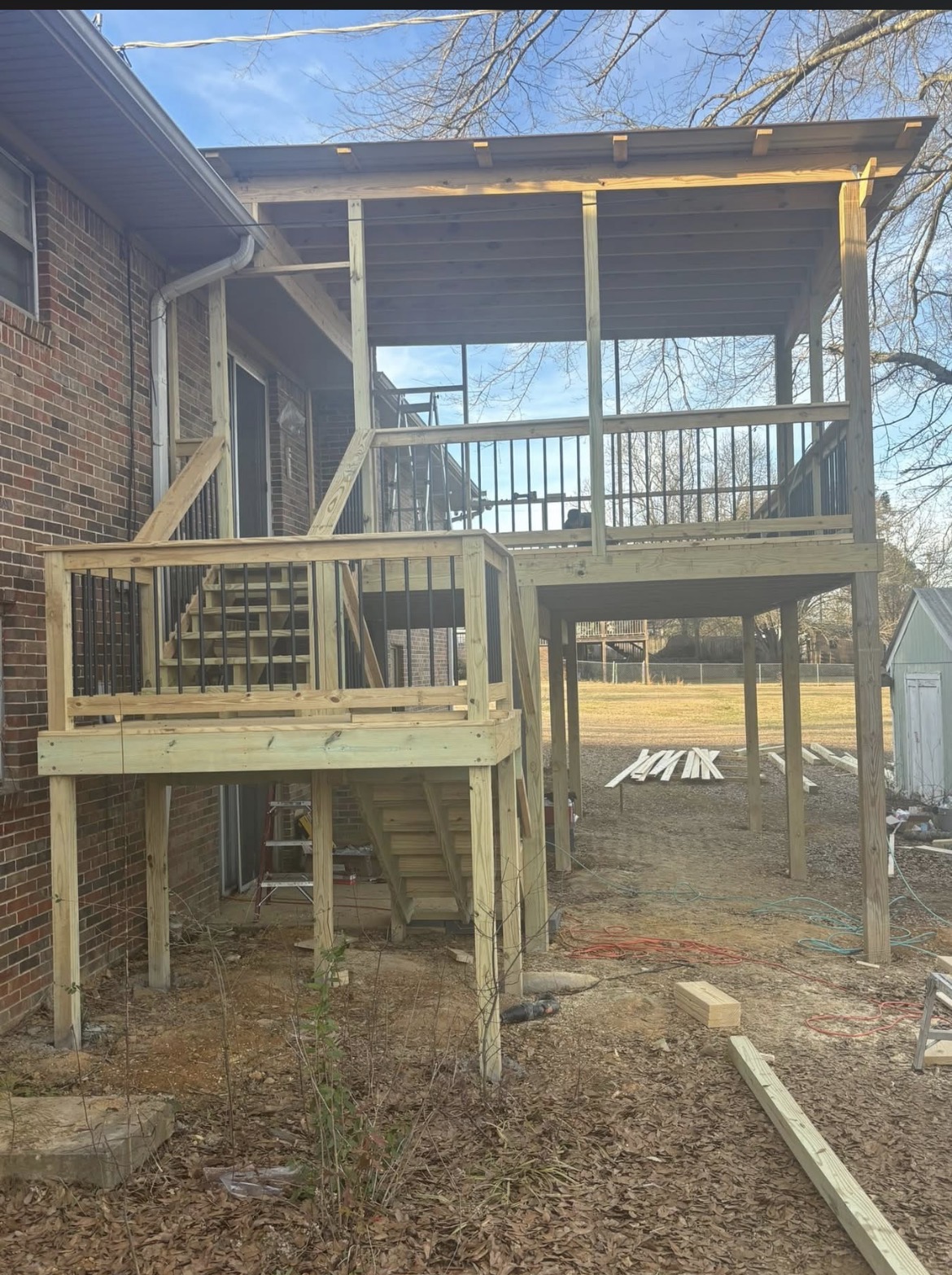 Two-story covered deck with black metal balusters, stairs and pressure-treated framing